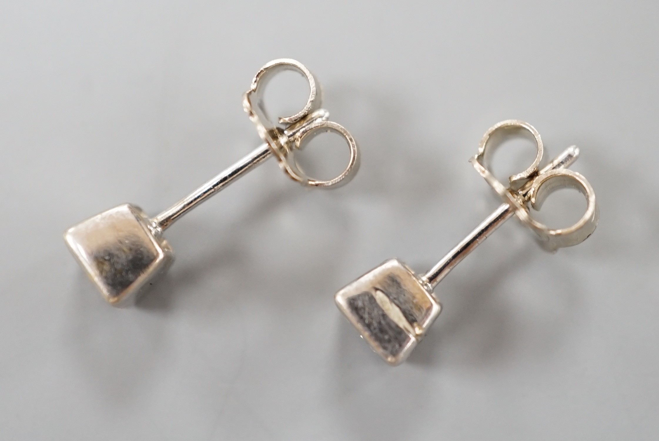 A pair of 750 white metal and princess cut solitaire diamond set ear studs, gross weight 2.4 grams.